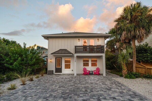 Here’s a beautiful sunset shot, with golden hues and fluffy pink clouds. Below, you can spot two pink chairs nestled under the outdoor balcony, which also features a cozy seating area. This serene space is just off the master bedroom suite 