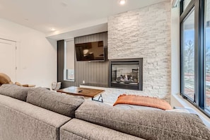 Open living space with gas fireplace, sofa sleeper, and Smart TV