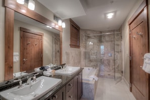 En suite bathroom with standing shower, soaking tub, and dual sinks