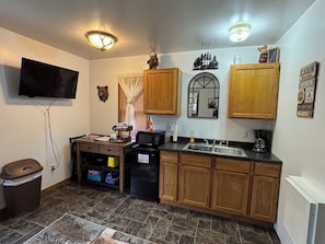 Kitchen with mini fridge, microwave, coffee pot, toaster, utensils, dinnerware