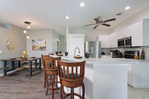 Kitchen with breakfast bar, stainless steel appliances, & dining table