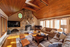 Relax in this grand living room with a stone fireplace & vaulted wood ceilings