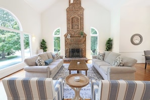 Living room with plenty of seating, large windows and fireplace