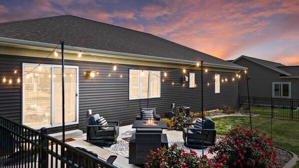 Quiet patio with luxury furniture, gas fireplace, string lights and corn hole.