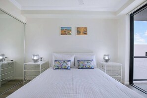 The primary bedroom has a cosy queen-sized bed that adjoins a sunlit balcony. 