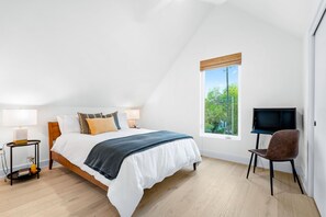 The airy queen bedroom offers a desk & tons of natural light