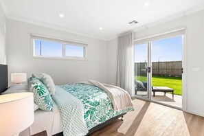 Bedroom 4 downstairs- Queen bed with built in robes and sliding doors opening onto the backyard.