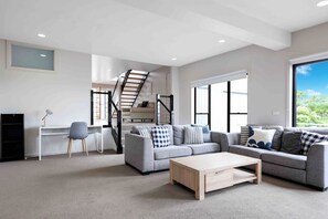 large second Lounge room with tv, comfy couches opens out to a second outdoor decking and secure grassy backyard.