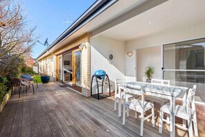 Opening large glass sliding doors to enjoy the entertaining deck complete with electric BBQ and outdoor furniture.