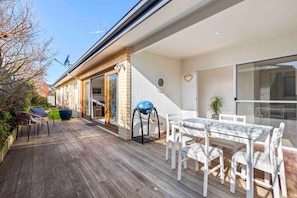 Opening large glass sliding doors to enjoy the entertaining deck complete with electric BBQ and outdoor furniture.