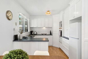 Ample modern kitchen with dishwasher, fridge, microwave, stove and cook top.