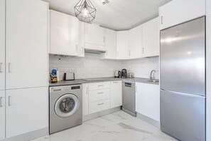 Kitchen with Stovetop, Oven, Fridge, Microwave, Dishwasher, Washing Machine, Coffee Maker, Electric Kettle and Toaster