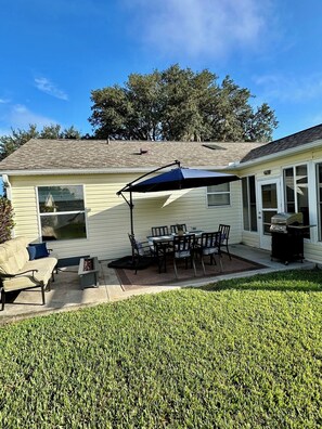 Patio has outdoor table, Couch with gas fire pit and gas grill with utensils. 