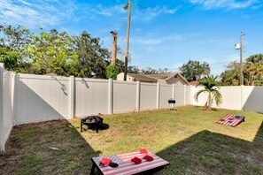 Fenced in backyard with firepit, charcoal grill and cornhole