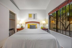 Bedroom with cozy queen bed, en-suite bathroom, closet, and views of the front patio
