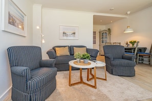 Wohnzimmer mit Sofa, Sessel und TV