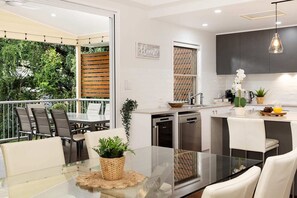 Dining table looking towards kitchen and upper balcony - wine fridge and dishwasher as well as other new appliances