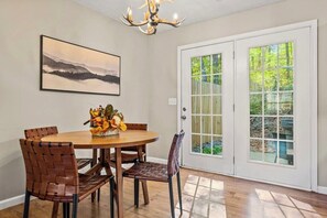 Your dining area offers the perfect backdrop for enjoying delicious meals with loved ones, with a large glass door showcasing the serene back patio and inviting hot tub.