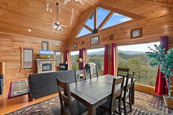 The spacious living room includes a fireplace, Smart TV, comfortable furniture, and beautiful Smoky Mountain views from the large fixed-glass windows.