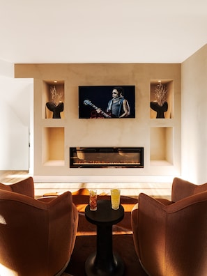 Cozy secondary living area features an electric fireplace, Smart TV, and warmer tones, providing the perfect intimate viewing experience.