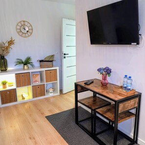 przytulny salon z TV oraz stół z dwoma krzesłami 