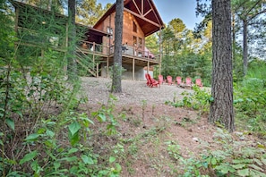 Outdoor Lounge: Gather around the fire pit in vibrant red chairs, surrounded by lush nature!
