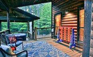 Spacious Porch: Enjoy scenic views, a relaxing hot tub, and fun games under the trees!
