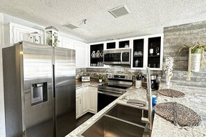 Full-sized fridge, deep double sinks, dishwasher, and fully stocked pots, pans, dishes, and utensils.