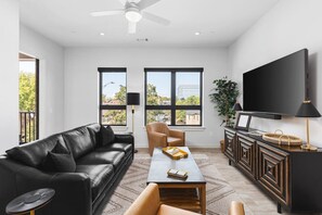 Comfortable living room with a Queen pull-out couch, room darkening shades, a Smart TV, and private patio in this corner unit condo on Music Row.