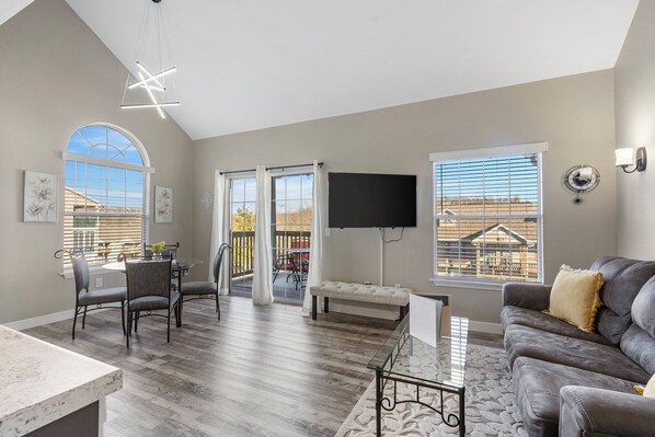 Bright open living space with sofa sleeper, Smart TV, and balcony access