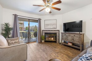 Open living space with TV, electric fireplace, Queen sofa sleeper, and patio access