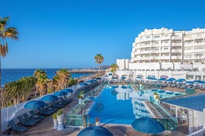 A stunning aerial view of a pool stretching towards the sea, lined with loungers for sun-soaked relaxation.