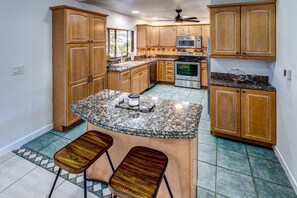 The kitchen is both functional and inviting, featuring a small island breakfast counter perfect for casual meals and morning coffee.