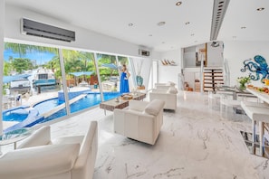 The open-concept living, dining, and chef's kitchen are bathed overlooking the tranquil canal and heated pool.