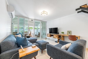 Open-space design with kitchen and dining area to one side, while on the other, leading out to a furnished patio.