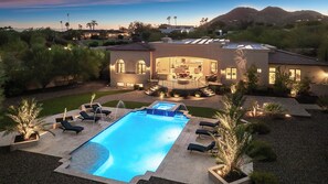 Luxurious estate with pool, spa, and scenic views, glowing beautifully at dusk.