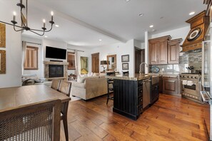View of living room and kitchen with luxury amenities and a fireplace and large tv
