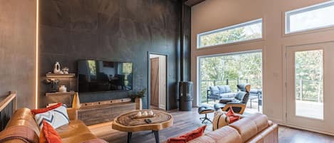 Living area with sectional sofa, TV, and views of the forested outdoors