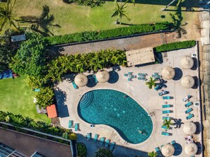 Royal Kahana 213’s pool is lined with loungers, palms, and tropical greenery.