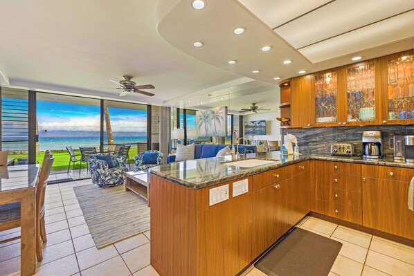 The open kitchen at Papakea L-106 features modern finishes and flows effortlessly into the living area and oceanfront lanai—perfect for relaxed island living