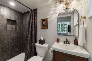 Spacious bathroom with varying textured tiling to match the moody theme with vanity storage for your toiletries