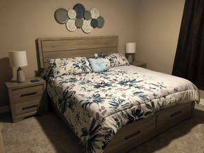 Primary bedroom features a king size bed and windows that look onto patio