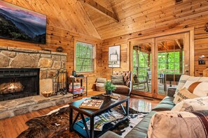 Living room with flatscreen tv, fireplace and surrounding forest views
