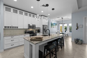 A fully equipped kitchen has granite countertops, an eat-in bar, and stainless steel appliances.