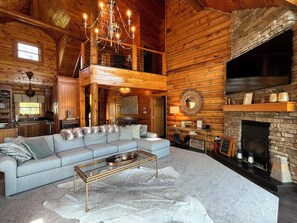 A view of the living area w/ large couch, 2 sitting chairs & wood burning FP.