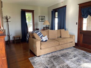 Living room with sofa bed and door to enclosed porch.
