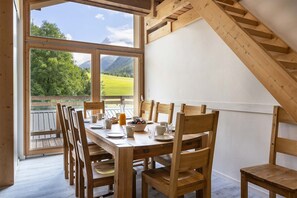 This inviting dining area offers a perfect space for enjoying meals with loved ones, with large windows showcasing the stunning outdoor scenery. The wooden furniture and high ceilings create a warm and welcoming atmosphere.