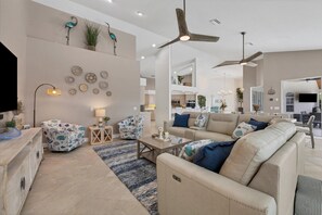 Open living space with ample seating, pool & water view, and 75-inch Smart TV