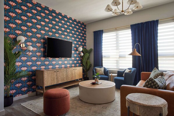 Lounge in a delightful living area adorned with lively floral wallpaper, cozy seating, and chic decor.