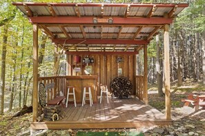 Unwind in your own private tiki bar surrounded by nature! This cozy outdoor setup, complete with a wooden bar and seating, is perfect for relaxing with drinks and enjoying the fresh air.